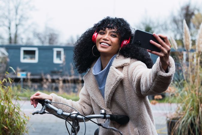 Delighted Black woman with smartphone on bicycle