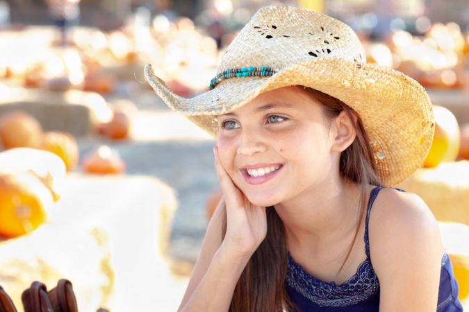 Girl Wearing Cowboy Hat Enjoying The Pumpkin Patch on a Sunny Fall Day.
