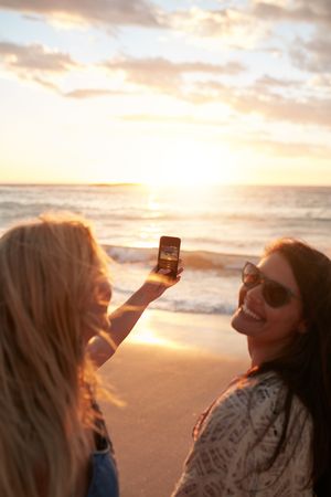 Women taking a photo of the sunset with mobile phone