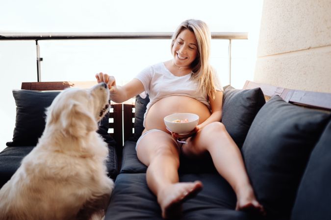 Smiling pregnant woman chilling with dog