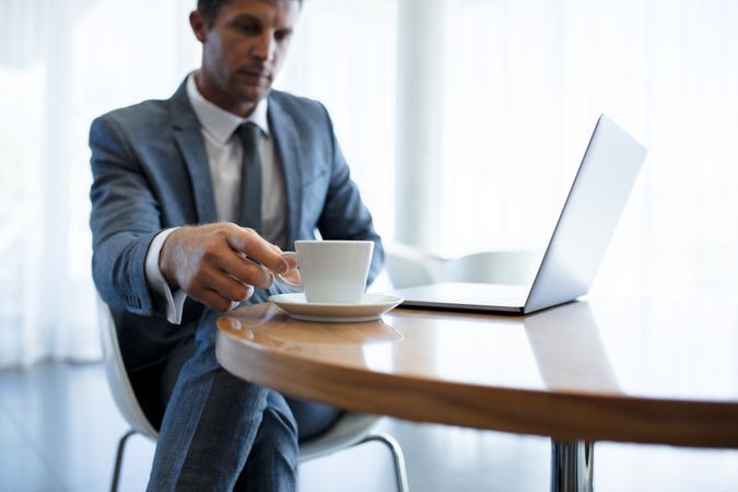 Businessman sitting at a table with laptop and coffee