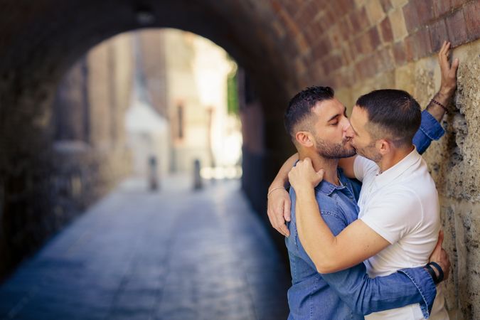 Two men sharing a kisss under a city bridge