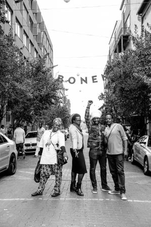 Group of friends stand in the street below sign that says Maboneng