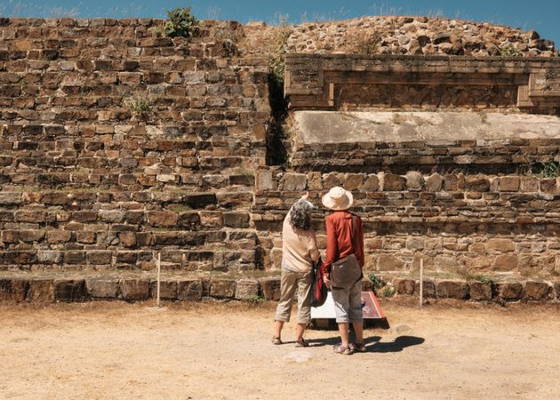 Back of two women looking up at building at Monte Alban, Mexico