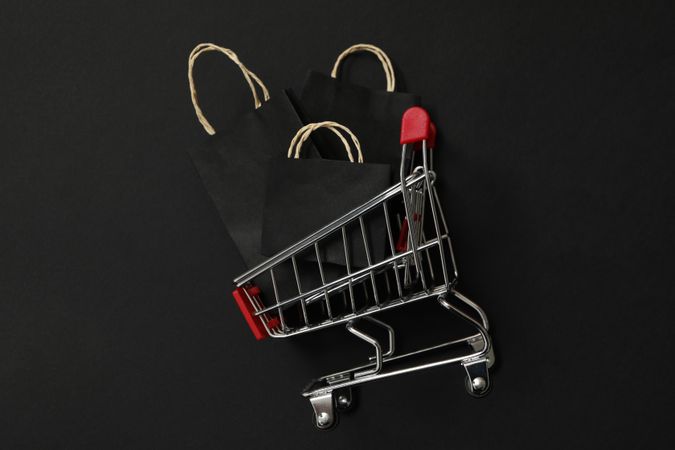 Shop trolley with paper bags on dark background