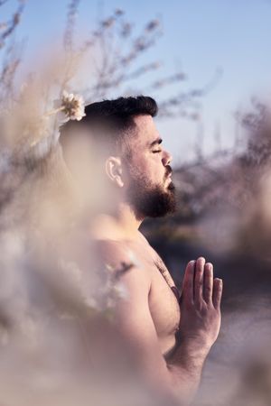 Shirtless man meditating in spring garden
