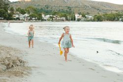 Little brother and sister walking on seaside in sunshine