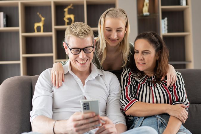 Father using mobile for online shopping or reading news sitting with daughter and wife