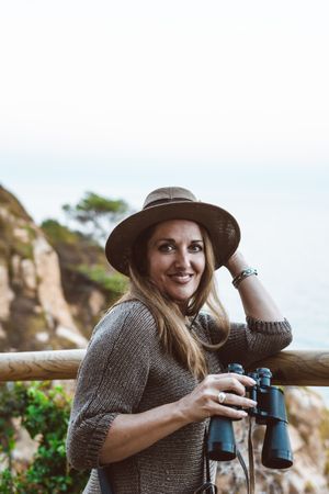 Woman with binocular on coastal walkway