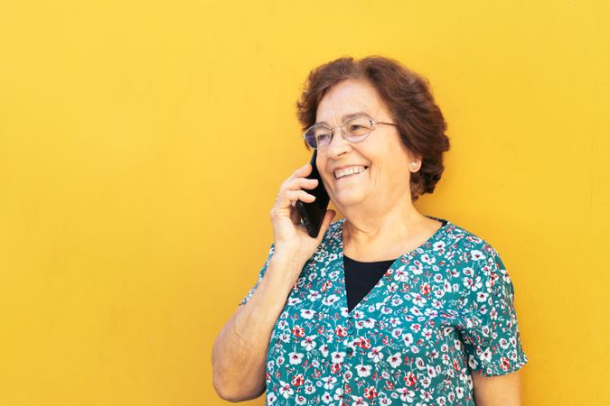 Cheerful older woman on a call outdoors