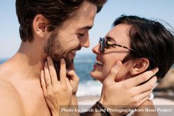 Couple holding each other to kiss standing on the beach 0KORV0