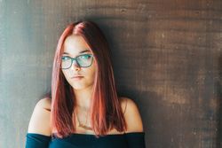 Woman in glasses leaning on wall