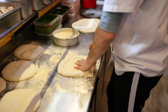 Baker's hands making pizza shape