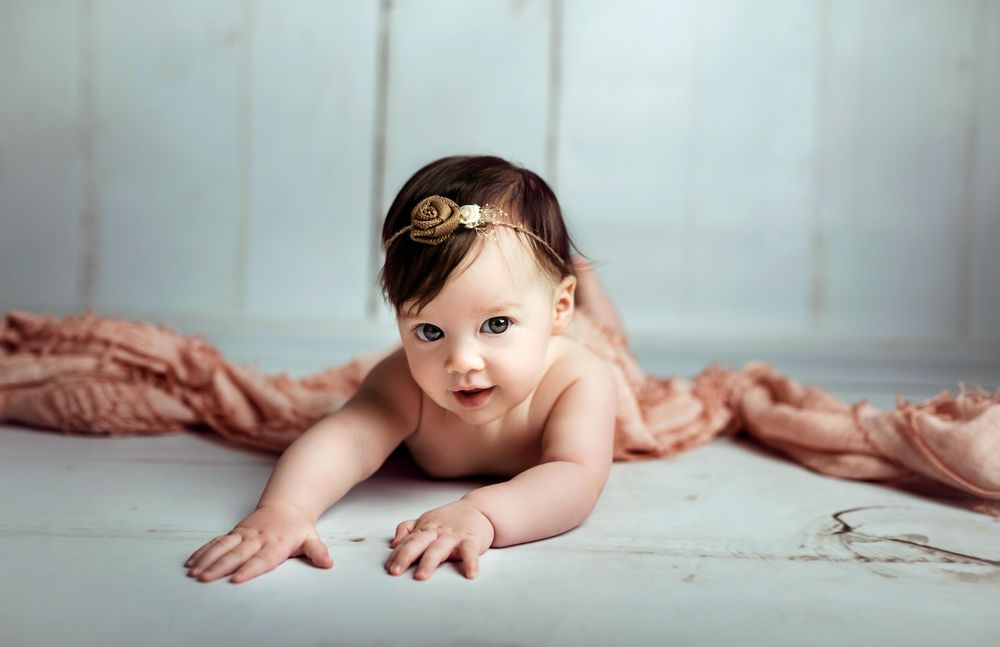 Baby girl on floor beside pink textile