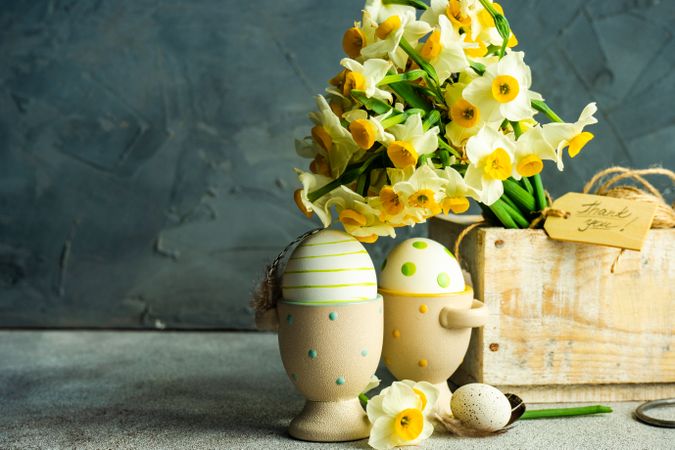 Side view of Easter floral card concept with daffodils and egg cups