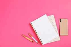 Stationery and smartphone on pink background, space for text