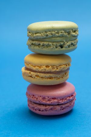 Stack of three French pastel macaroons on a blue table