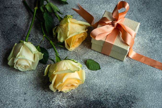 Yellow flowers on grey counter with gift wrapped in peach ribbon