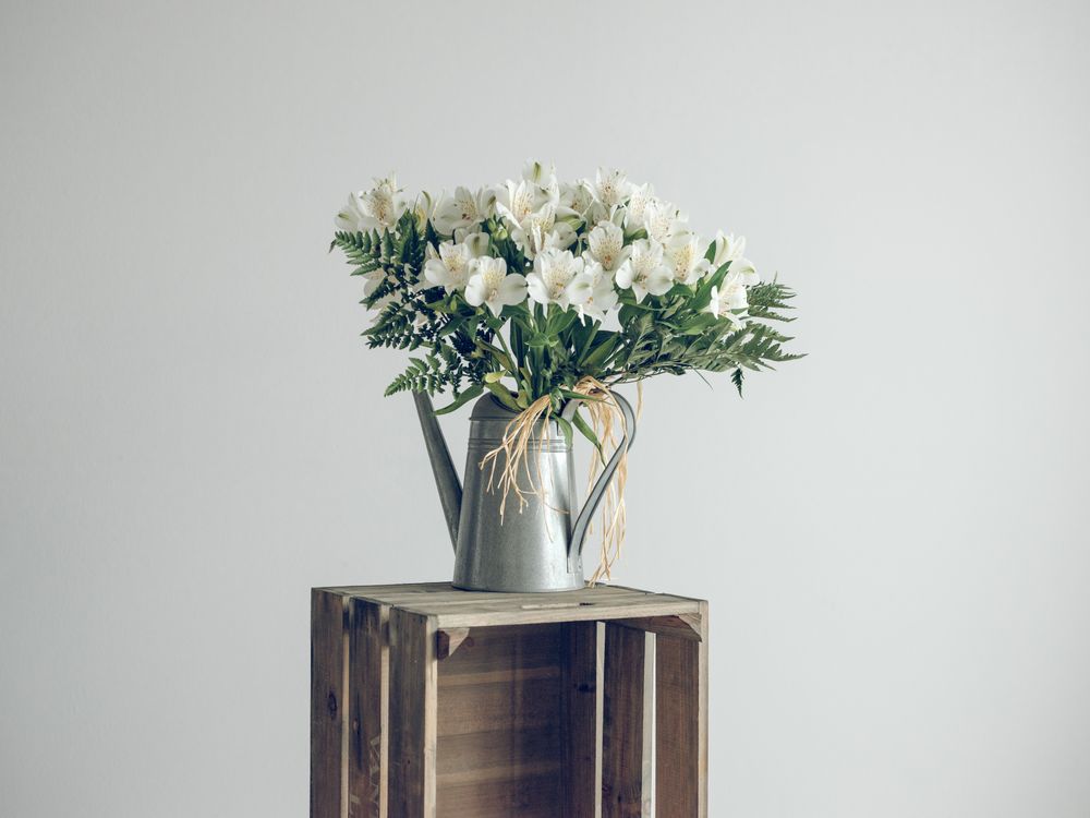 flowers in watering can on crate