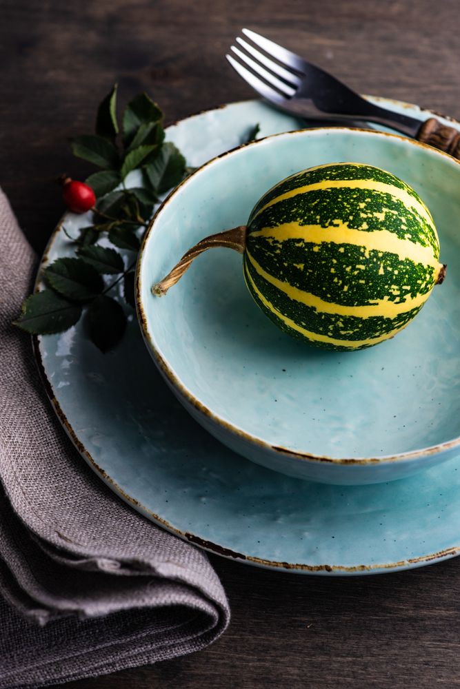 Thanksgiving table setting with close up of squash in light blue bowl