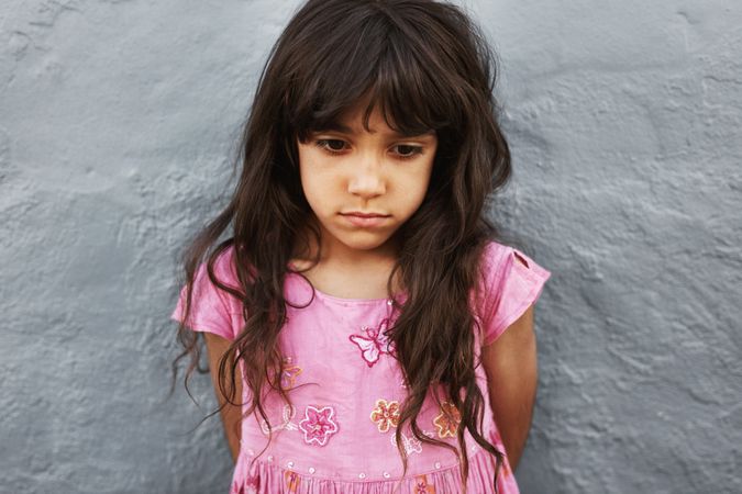 Close up portrait of little girl standing looking upset