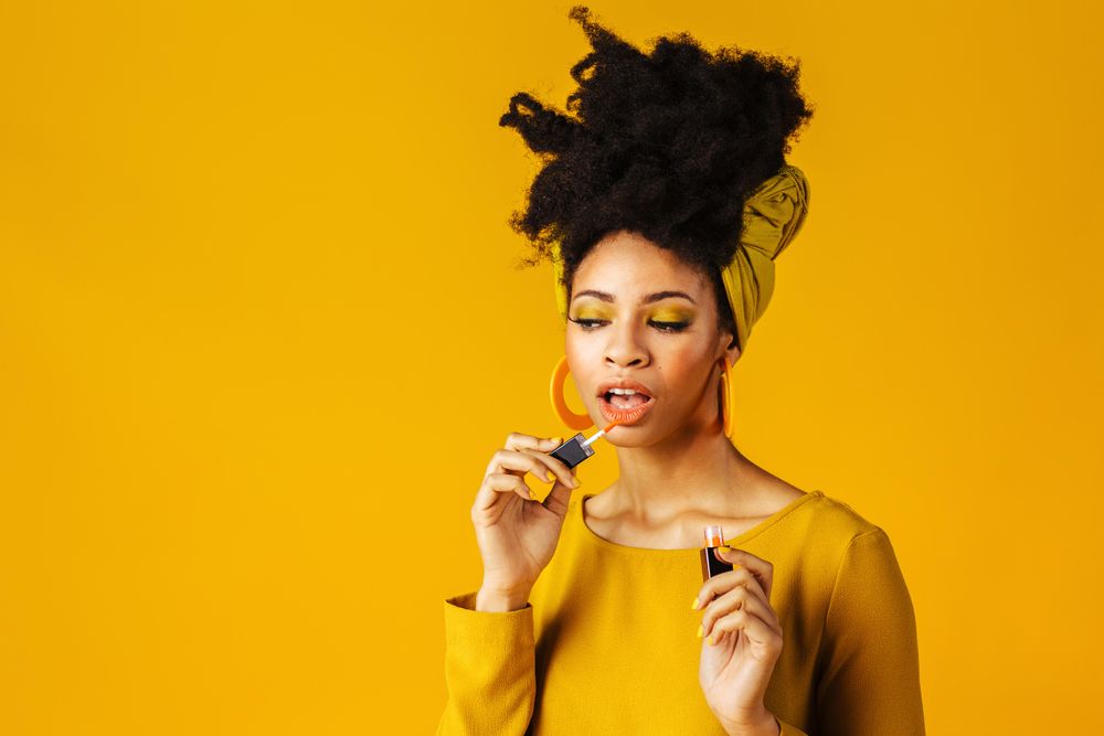 Portrait of Black woman applying lipgloss