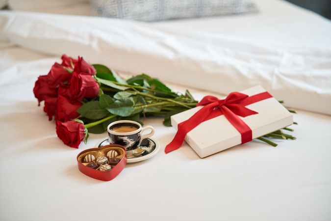 Composition of gift and coffee bouquet of roses on bed