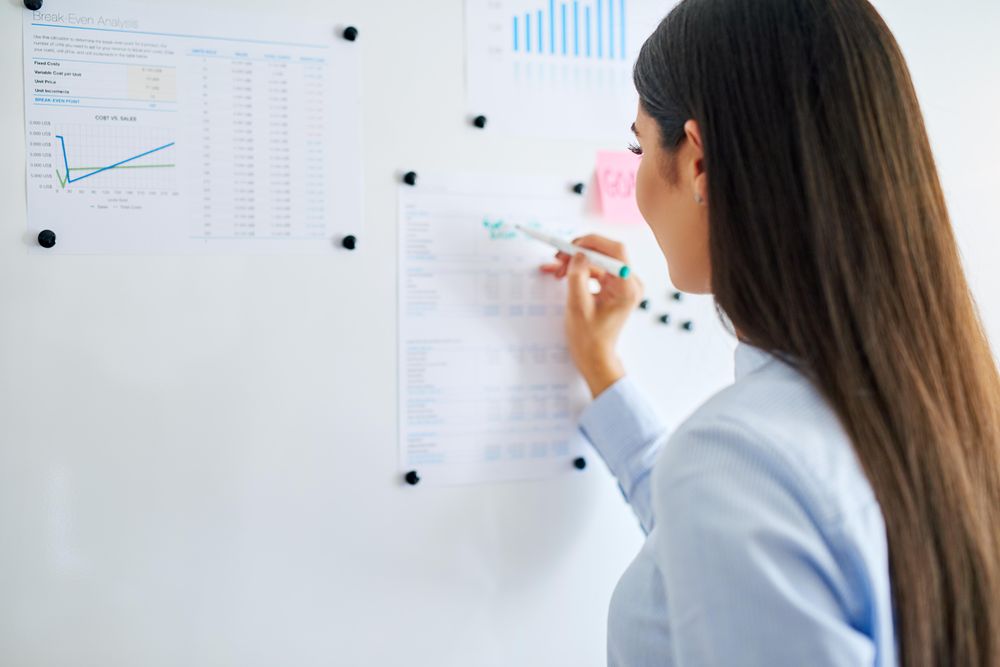 Businesswoman brainstorming on a dry erase board in bright office