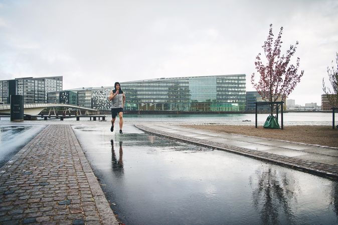 Man in grey vest jogging outside on rainy day