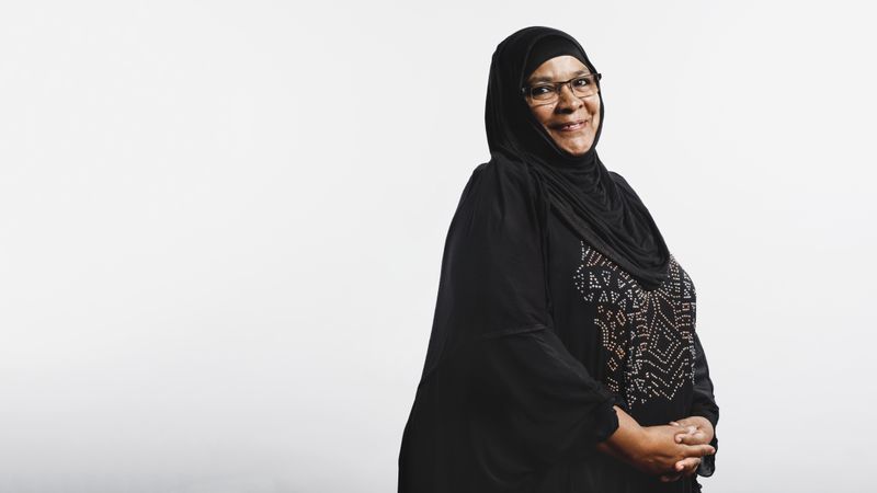 Smiling arabic woman in eyeglasses and hijab looking at camera
