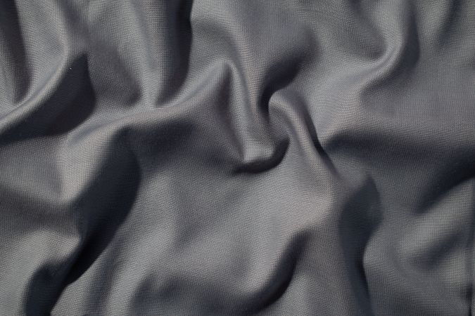 Crumpled wavy dark grey silky fabric background texture. siny and glossy.
