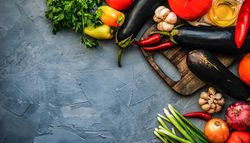 Eggplants and fresh bright vegetables on kitchen counter