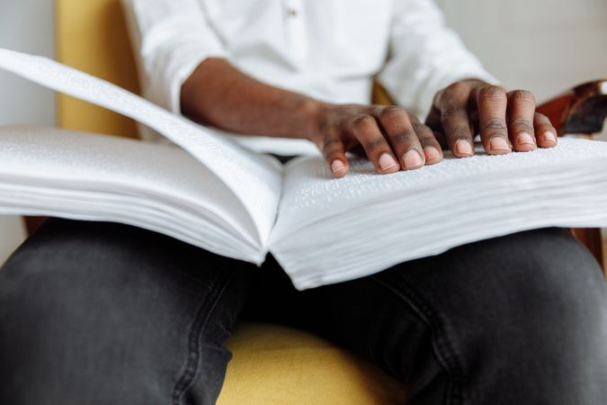 Young man reading a book using braille system