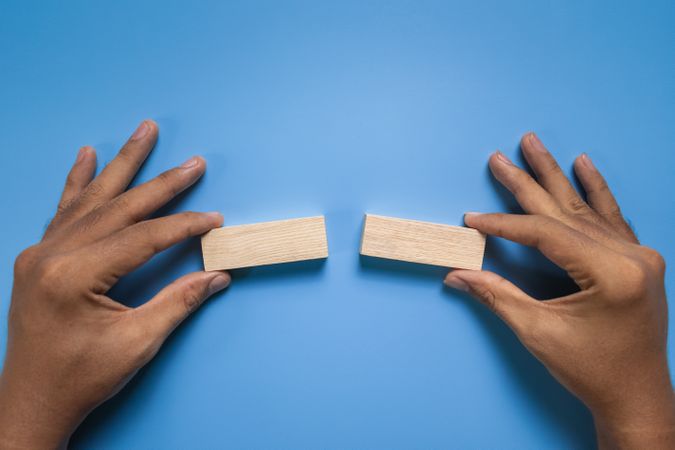 male hands hold two blank wooden blocks isolated on blue background