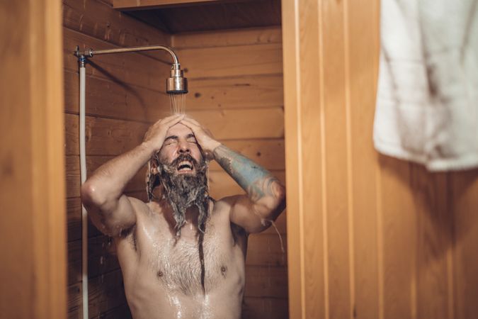 Man taking shower in wooden bathroom