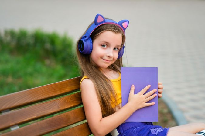 Preteen school girl with book on bench in park