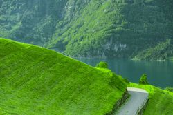 Path on green hill with lake and mountain in background