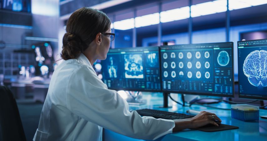 Hospital Research Laboratory: Female Medical Scientist Using Computer with Brain Scan MRI Images.