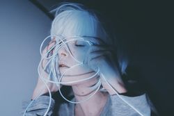 Portrait of woman with light hair holding blue led light thread closing her eyes