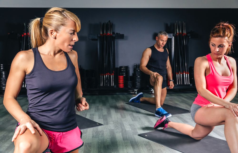 Woman trainer teaching exercises to fitness class in a sports center