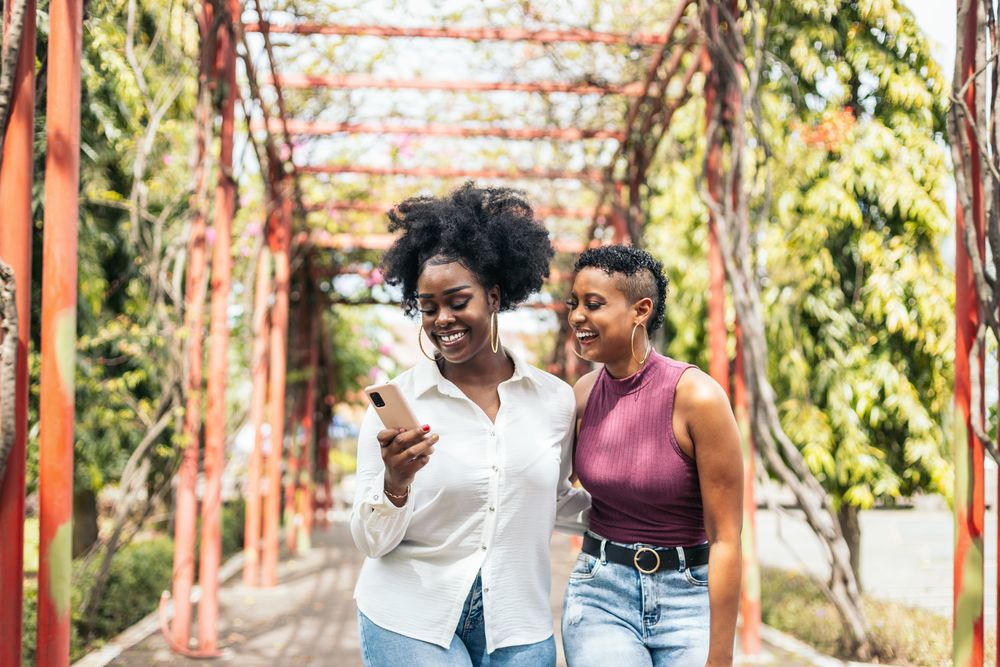 Happy women taking selfies with smartphone walking in the park