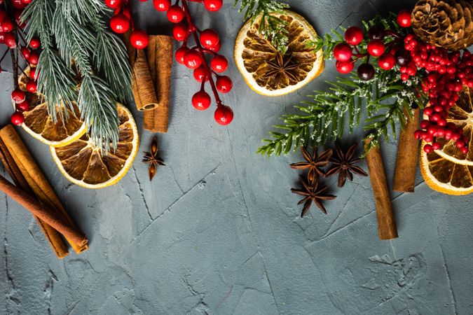 Christmas frame with fir tree, red berries and dried orange slices on concrete background with copy space
