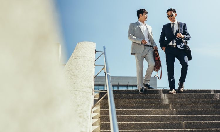 Two business partners walking together down stairs in the city