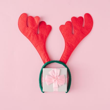 Christmas present with reindeer antlers on pink background