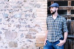 Casual man standing against a brick wall while looking away