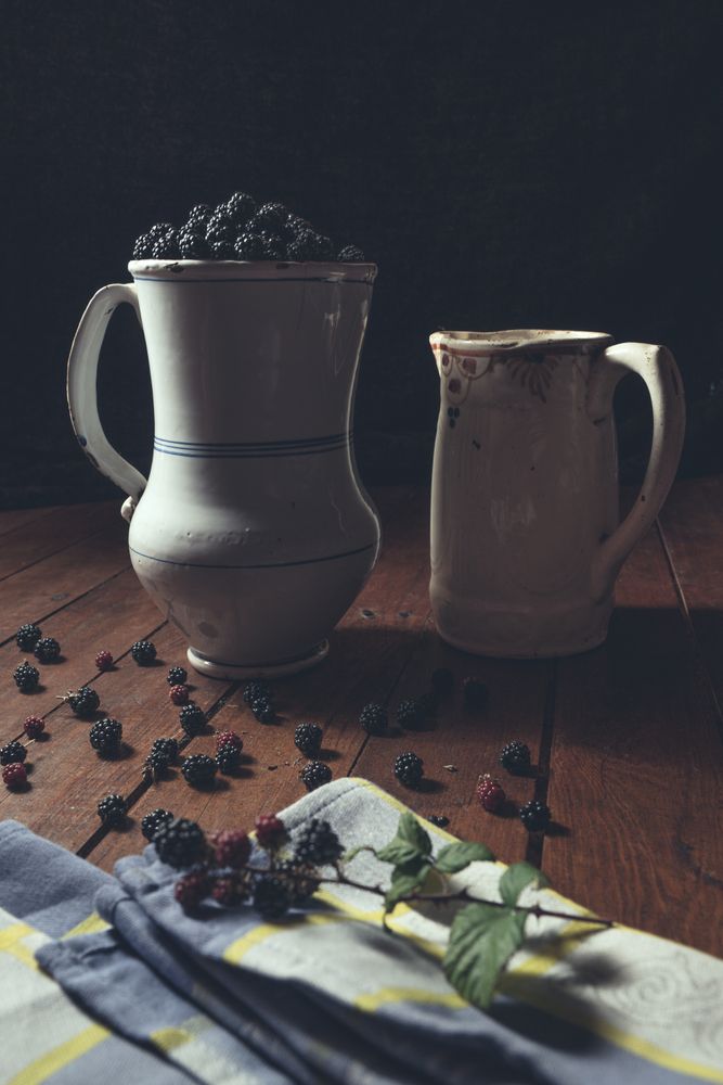 Vintage jag with ripe blackberries on wood and leaves on a old book