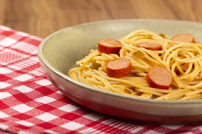 spaghetti pasta with sliced sausages and tomato sauce.