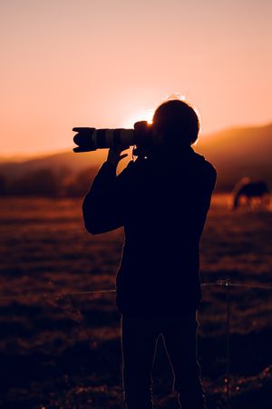 Man shooting on camera beautiful landscape between hills