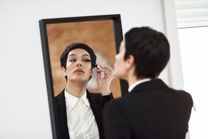 Woman wearing suit with blazer jacket doing her make up
