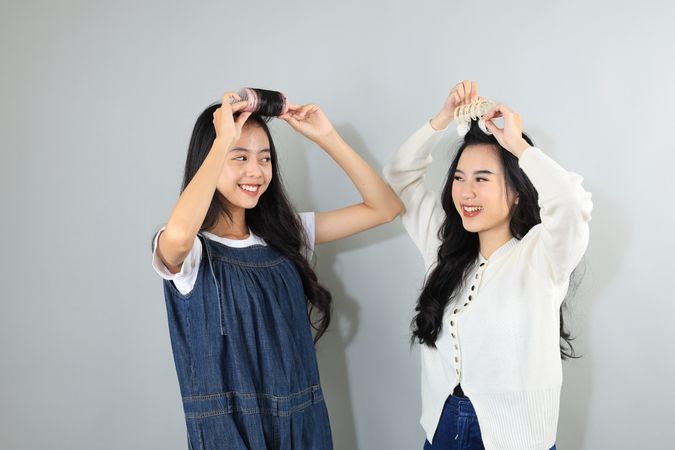 Two Young Asian Female Friend Smiling While Styling Hers Hair Bangs with Roller